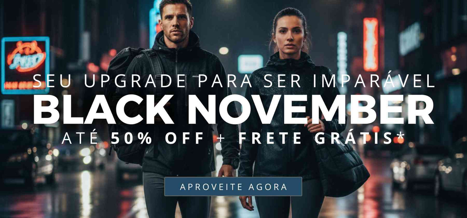 Banner de Black November da Urbanno para desktop. A imagem de fundo mostra um casal de atletas, um homem e uma mulher, caminhando com determinação em uma rua urbana à noite, sob a chuva, com luzes de neon ao fundo. Sobreposto à imagem, o texto principal diz: "SEU UPGRADE PARA SER IMPARÁVEL. BLACK NOVEMBER. ATÉ 50% OFF + FRETE GRÁTIS*". Abaixo, há um botão de ação com o texto "APROVEITE AGORA". A atmosfera é cinematográfica e focada em performance.