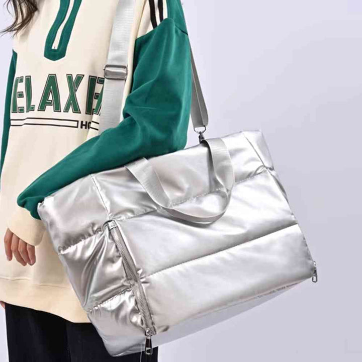 Pessoa usando a Bolsa de Academia Feminina Grande para Yoga com Compartimento para Mat Prata Urbanno no ombro, com alça transversal, destacando seu brilho e design moderno em uso.