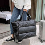 Pessoa carregando a Bolsa de Academia Feminina Grande para Yoga com Compartimento para Mat Preta Urbanno pela alça de mão, ao lado de uma mala de viagem, demonstrando sua praticidade para viagens ou transporte.