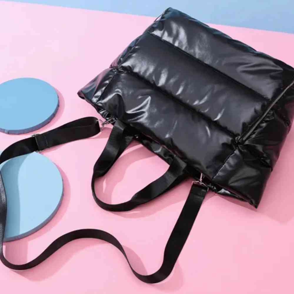 Bolsa de Academia Feminina Grande para Yoga com Compartimento para Mat Preta Urbanno, estilo tote acolchoada, vista de cima em ângulo diagonal, destacando suas alças e a textura do material em um fundo colorido.