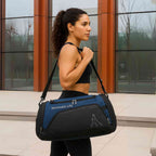 Mulher em roupa de ginástica preta usando a Bolsa de Academia Grande com Compartimento de Sapatos Azul Escuro Urbanno, carregada no ombro, demonstrando seu uso elegante e prático no dia a dia.