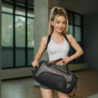 mulher carregando a Bolsa de Academia Grande com Compartimento de Sapatos Cinza Grafite Urbanno pela alça, subindo escadas, demonstrando a praticidade de transporte no dia a dia.