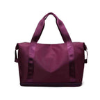 Bolsa de Academia e Viagem Feminina Leve Expansível Vinho Urbanno, vista frontal em seu estado compacto, com alças duplas e etiqueta da marca, pronta para ser expandida e usada.