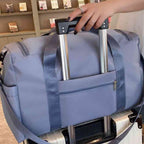 Bolsa de Academia e Viagem Feminina Multifuncional Azul Urbanno, acoplada à alça retrátil de uma mala de viagem, demonstrando sua praticidade para transporte em aeroportos e viagens.
