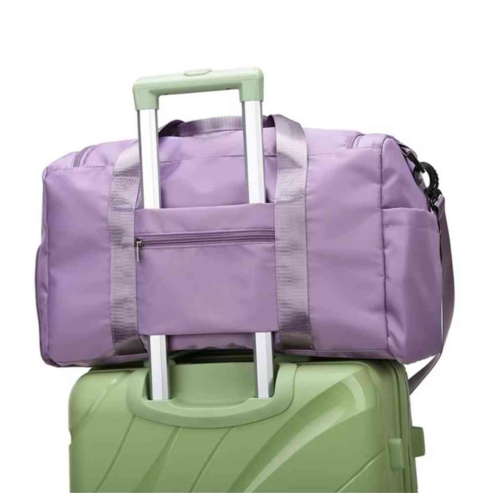 Bolsa de Academia e Viagem Feminina Multifuncional Roxa Urbanno, acoplada à alça retrátil de uma mala de viagem verde, sendo transportada, demonstrando sua praticidade para viagens.