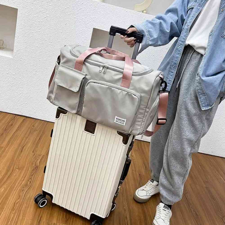 Bolsa de Academia e Viagem Feminina Multifuncional Verde Menta com Alça Rosa Urbanno, acoplada à alça de uma mala clara, sendo transportada por uma pessoa, demonstrando a praticidade para viagens.