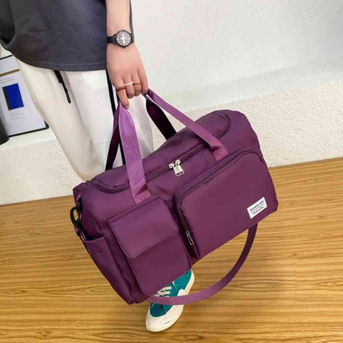 Bolsa de Academia e Viagem Feminina Multifuncional Vinho Urbanno, sendo carregada na mão por uma pessoa com calça clara, demonstrando o tamanho e praticidade para uso diário ou viagens.