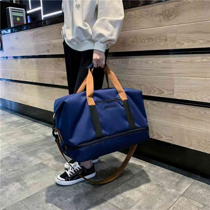 Bolsa de Academia e Viagem Grande com Compartimento de Sapatos Azul Urbanno, sendo carregada por uma pessoa pela alça de ombro, demonstrando seu tamanho e a praticidade de transporte.