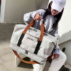 Bolsa de Academia e Viagem Grande com Compartimento de Sapatos Cinza Urbanno, sendo carregada por uma mulher pela alça de mão marrom, demonstrando seu tamanho e praticidade.