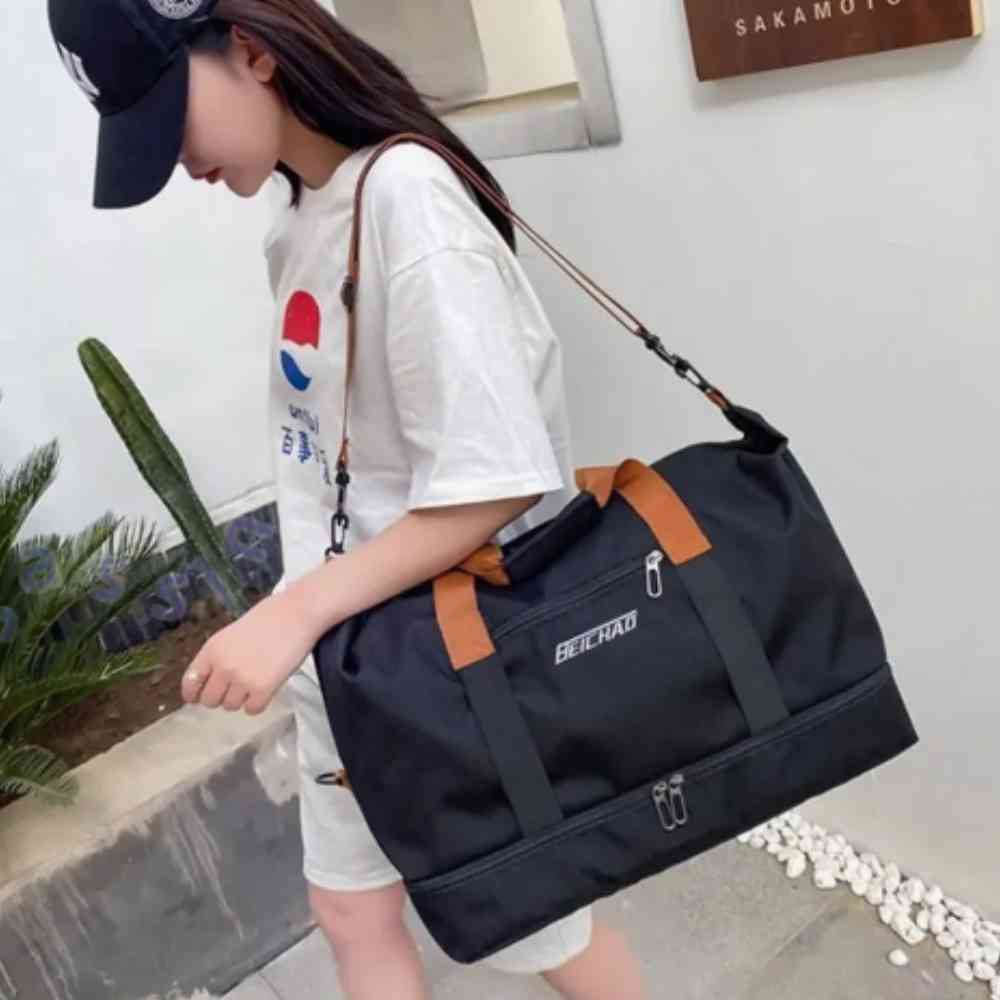 Bolsa de Academia e Viagem Grande com Compartimento de Sapatos Preta Urbanno, sendo usada por uma mulher de boné e camiseta, carregando-a no ombro, demonstrando seu tamanho e praticidade em uso.