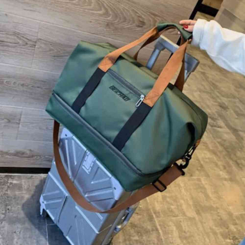 Bolsa de Academia e Viagem Grande com Compartimento de Sapatos Verde Urbanno, acoplada à alça retrátil de uma mala de viagem prateada, demonstrando a praticidade para transporte em viagens.