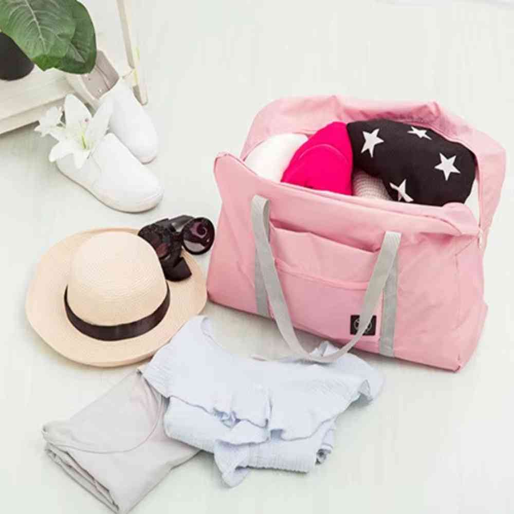 Bolsa de Academia e Viagens Dobrável Rosa Salmão Urbanno, aberta, com roupas e acessórios de viagem ao redor, demonstrando sua capacidade e facilidade para organizar pertences.