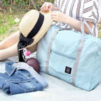 Bolsa de Academia e Viagens Dobrável Verde Água Urbanno, em um cenário de piquenique com chapéu, casaco e outros itens, demonstrando sua versatilidade para diversas atividades ao ar livre.