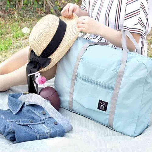 Bolsa de Academia e Viagens Dobrável Verde Água Urbanno, em um cenário de piquenique com chapéu, casaco e outros itens, demonstrando sua versatilidade para diversas atividades ao ar livre.