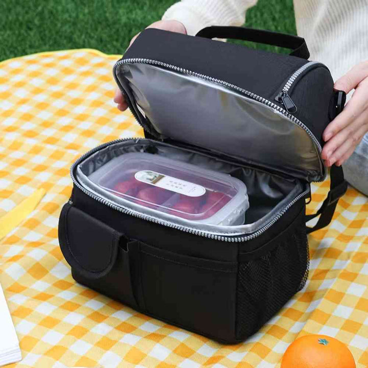Bolsa Térmica Grande para Marmita com Duplo Compartimento 10L Urbanno preta, aberta em toalha de piquenique xadrez, com uma marmita de frutas dentro, ideal para refeições ao ar livre urbanno