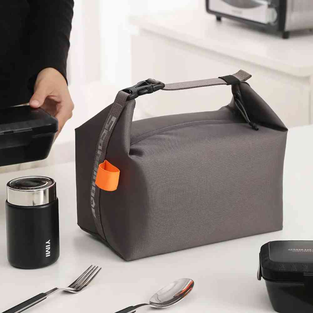  Bolsa Térmica Minimalista Urbanno cinza em bancada de cozinha, com uma pessoa pegando a marmita e um pote térmico ao lado