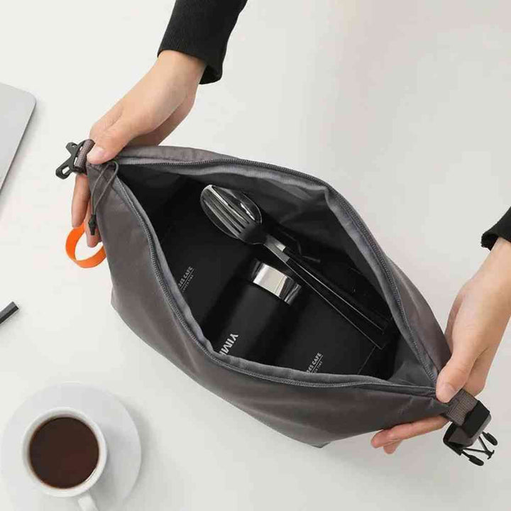 Bolsa Térmica Minimalista Urbanno cinza aberta, com mãos segurando e mostrando o interior com pote térmico e talheres