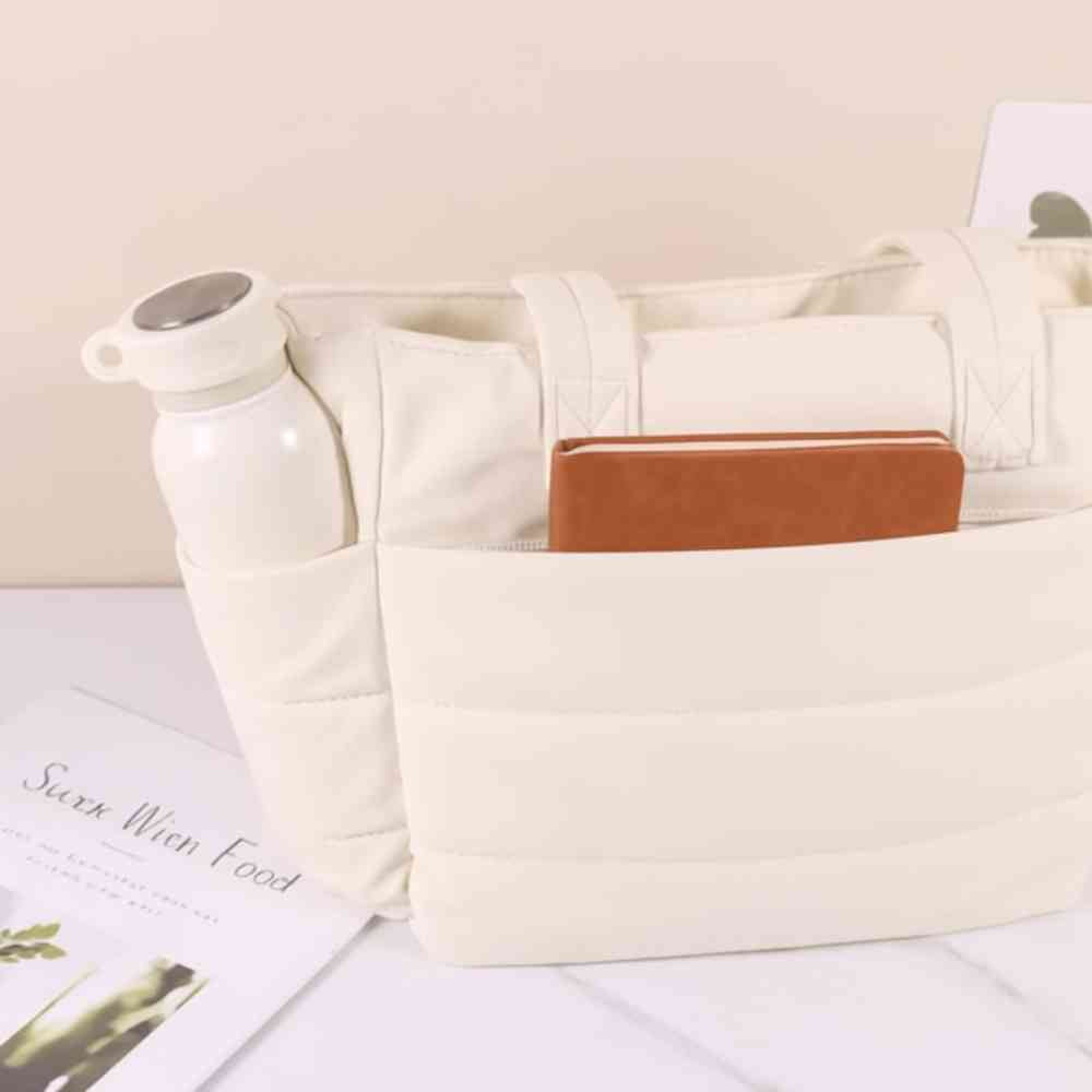 Bolsa Tote de Academia e Dia a Dia Feminina Acolchoada Urbanno branca, mostrando bolsos externos com garrafa branca e caderno, destacando organização
