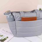 Bolsa Tote de Academia e Dia a Dia Feminina Acolchoada Urbanno cinza, mostrando bolsos externos com garrafa cinza e caderno marrom, destacando a organização