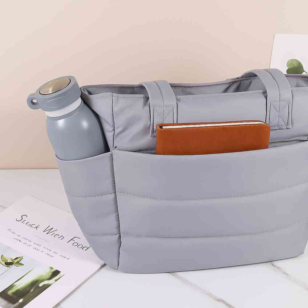 Bolsa Tote de Academia e Dia a Dia Feminina Acolchoada Urbanno cinza, mostrando bolsos externos com garrafa cinza e caderno marrom, destacando a organização