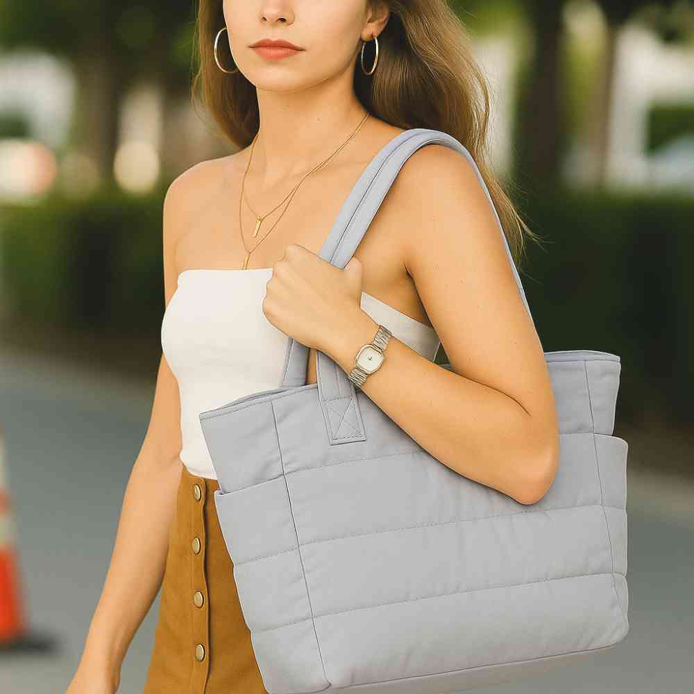 Mulher usando a Bolsa Tote de Academia e Dia a Dia Feminina Acolchoada Urbanno cinza no ombro, demonstrando estilo e praticidade em ambiente urbano
