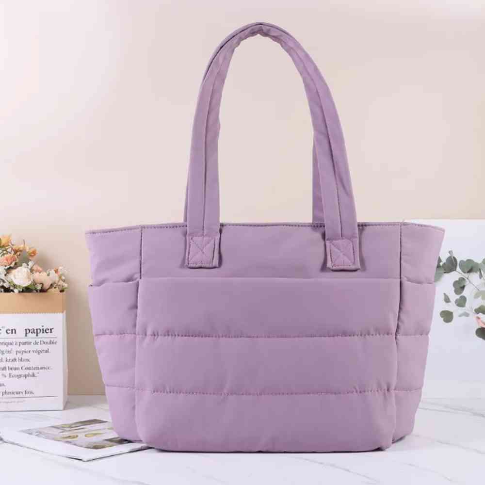 Bolsa Tote de Academia e Dia a Dia Feminina Acolchoada Urbanno lilás, em ambiente interno com flores e livro decorativo ao fundo