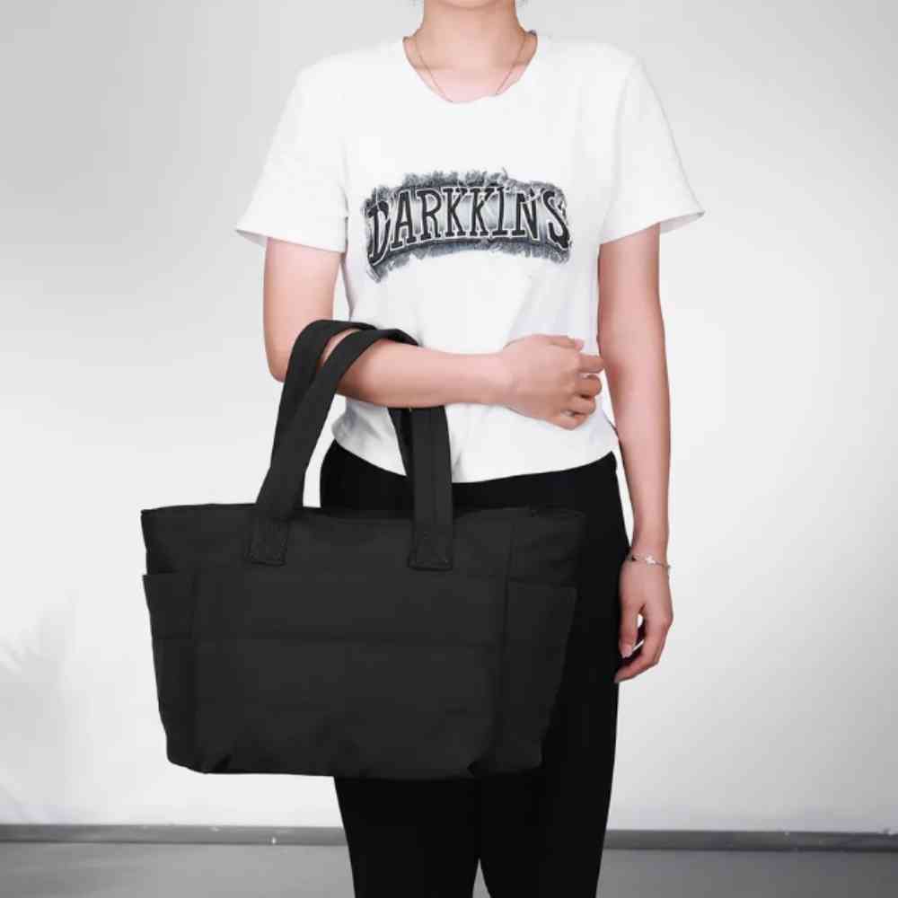 Mulher segurando a Bolsa Tote de Academia e Dia a Dia Feminina Acolchoada Urbanno preta, demonstrando seu tamanho e design ao corpo