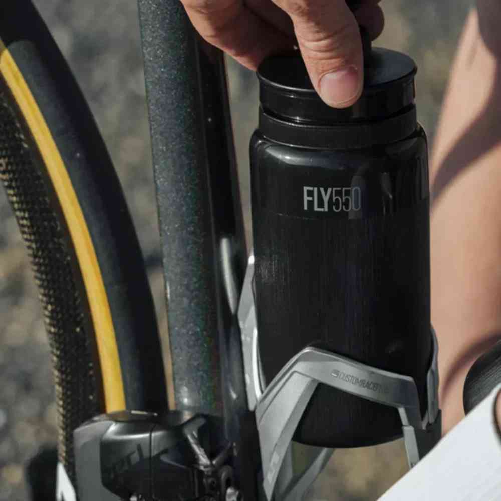 Caramanhola de Ciclismo Ultraleve FLY550 550ml Urbanno preta, sendo colocada ou retirada do suporte de bicicleta durante o uso