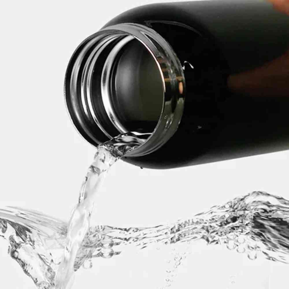 Garrafa de Academia Térmica com Canudo e Alça 500ml Urbanno preta, água sendo despejada do bocal, demonstrando facilidade de uso para hidratação