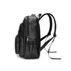 Mochila Notebook 15.6" em Couro PU Minimalista USB Preta Urbanno, vista lateral, mostrando seu perfil elegante, as alças de ombro ajustáveis, bolsos laterais e a entrada USB externa.