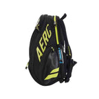 Mochila Raqueteira Babolat AERO Preta com amarelo da loja online Urbanno, vista lateral, mostrando compartimentos laterais, alças acolchoadas e logotipos, ideal para transporte de equipamentos esportivos