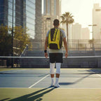 homem entrando em quadra usando a Mochila Raqueteira Babolat amarela e preta da Urbanno, demonstrando uso para esporte em quadra.