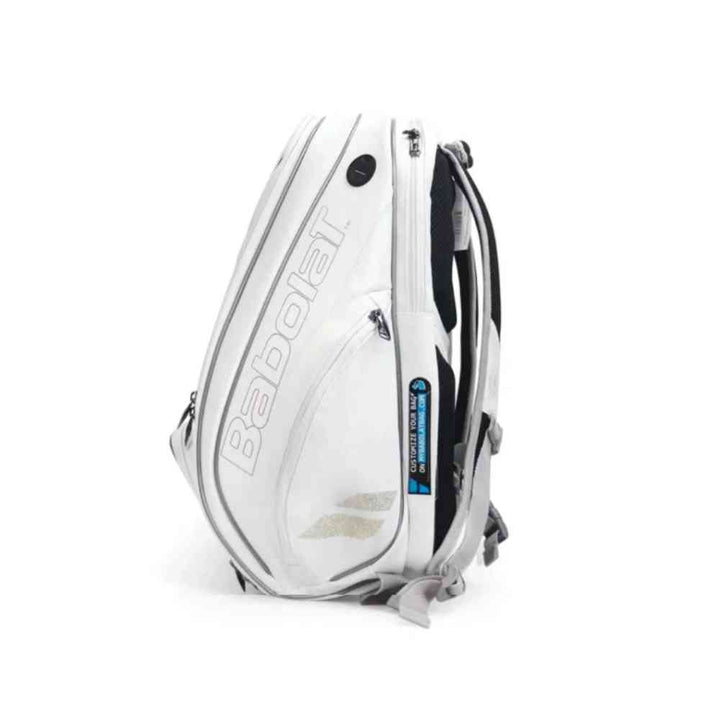 Mochila Raqueteira Babolat Branca e Dourada Urbanno, vista lateral, mostrando compartimentos laterais, alças acolchoadas e logotipos, ideal para transporte de equipamentos esportivos urbanno