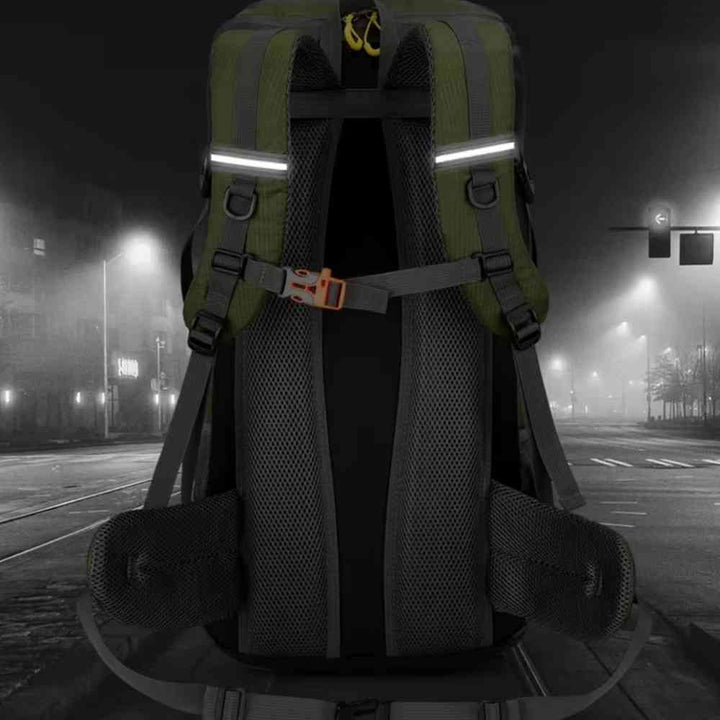 Mochila de Viagem e Camping 50L Aventura Impermeável Urbanno verde oliva, vista traseira em ambiente noturno iluminado por postes, destacando as faixas refletivas nas alças, ideal para segurança em condições de baixa luz urbanno