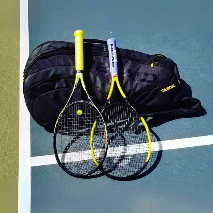 Raqueteira Head Radical CCT para 6 Raquetes de Tênis Preta Urbanno, posicionada em uma quadra de tênis ao lado de duas raquetes, demonstrando seu uso em ambiente esportivo