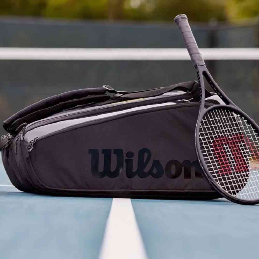 Raqueteira Wilson para 9 Raquetes com Proteção Térmica Preta Urbanno, posicionada em uma quadra de tênis com uma raquete ao lado, pronta para o jogo.
